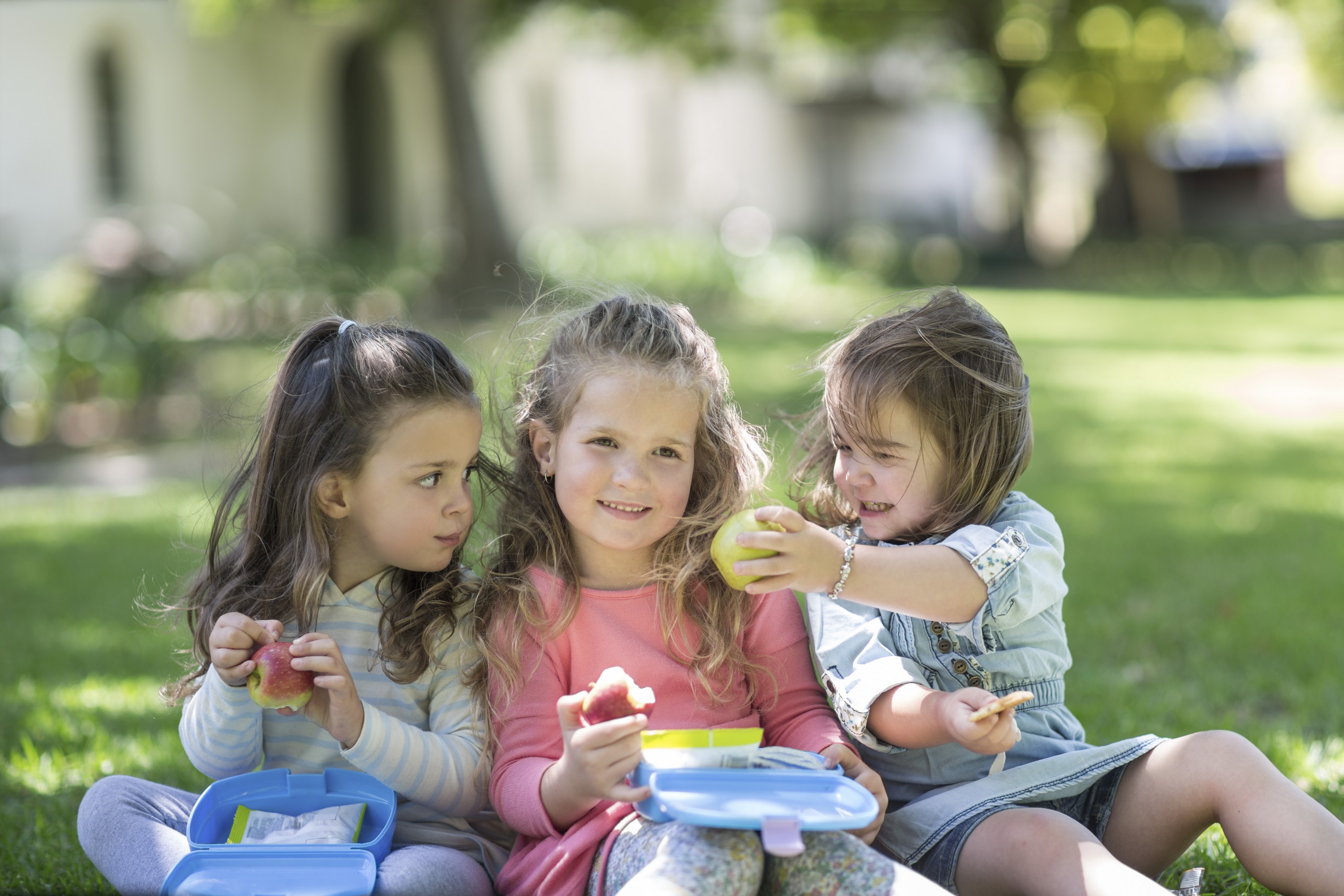 Toddler girls in a garden sharing lunch