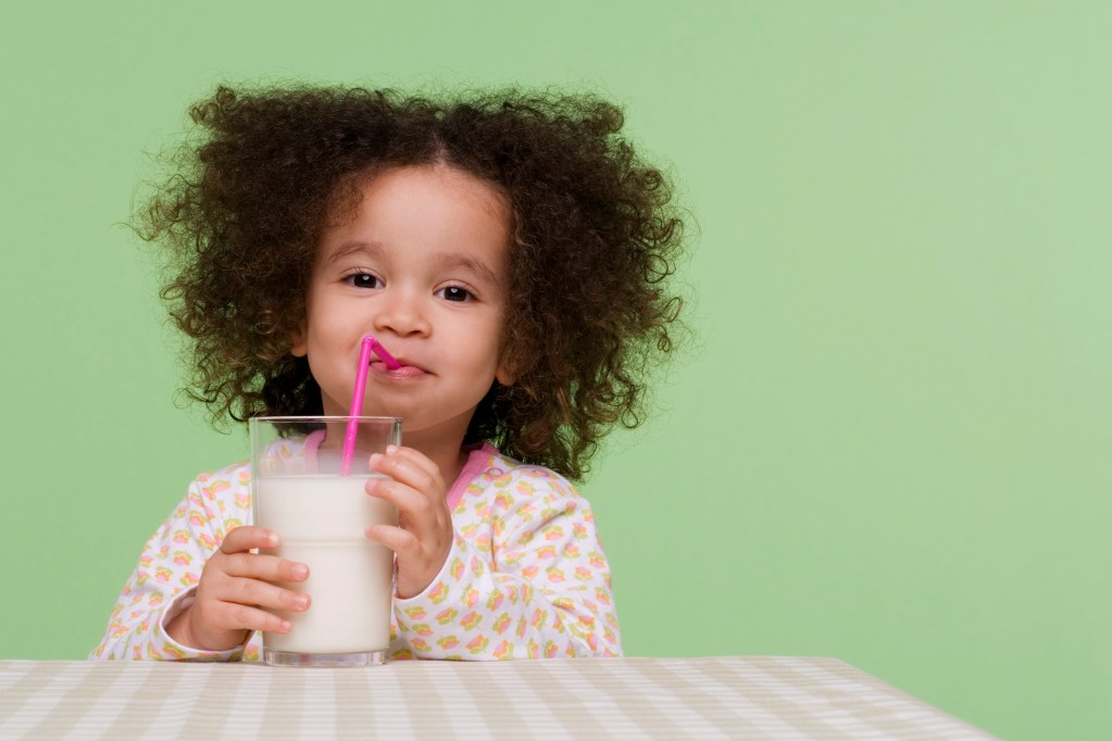 toddler girl drinking milk from a straw