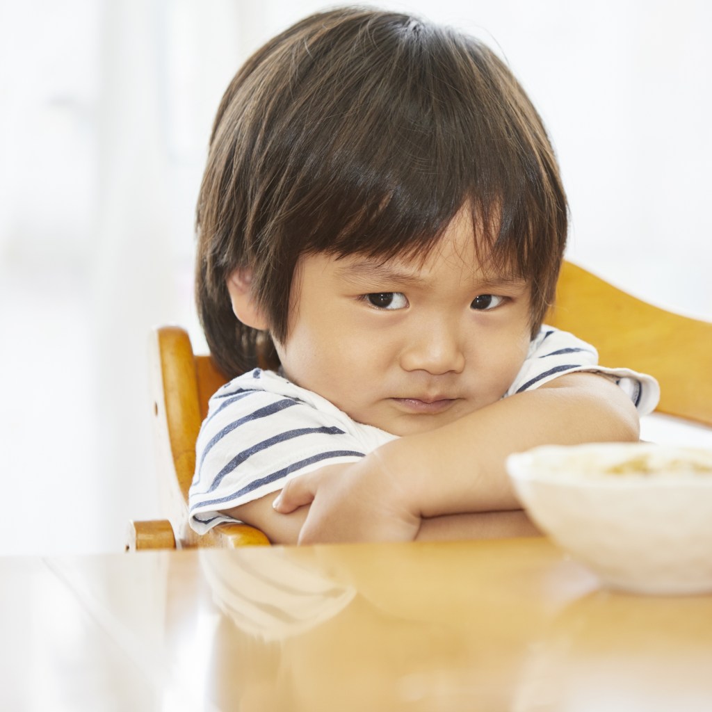 Boy sitting in a chair and refusing to eat
