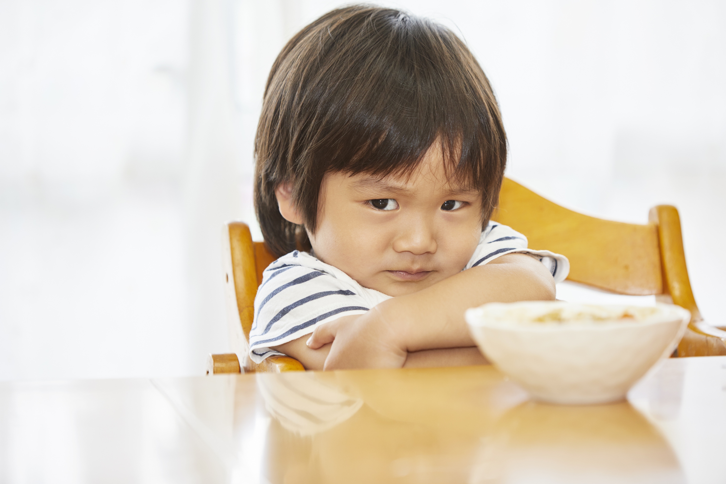 Boy sitting in a chair and refusing to eat
