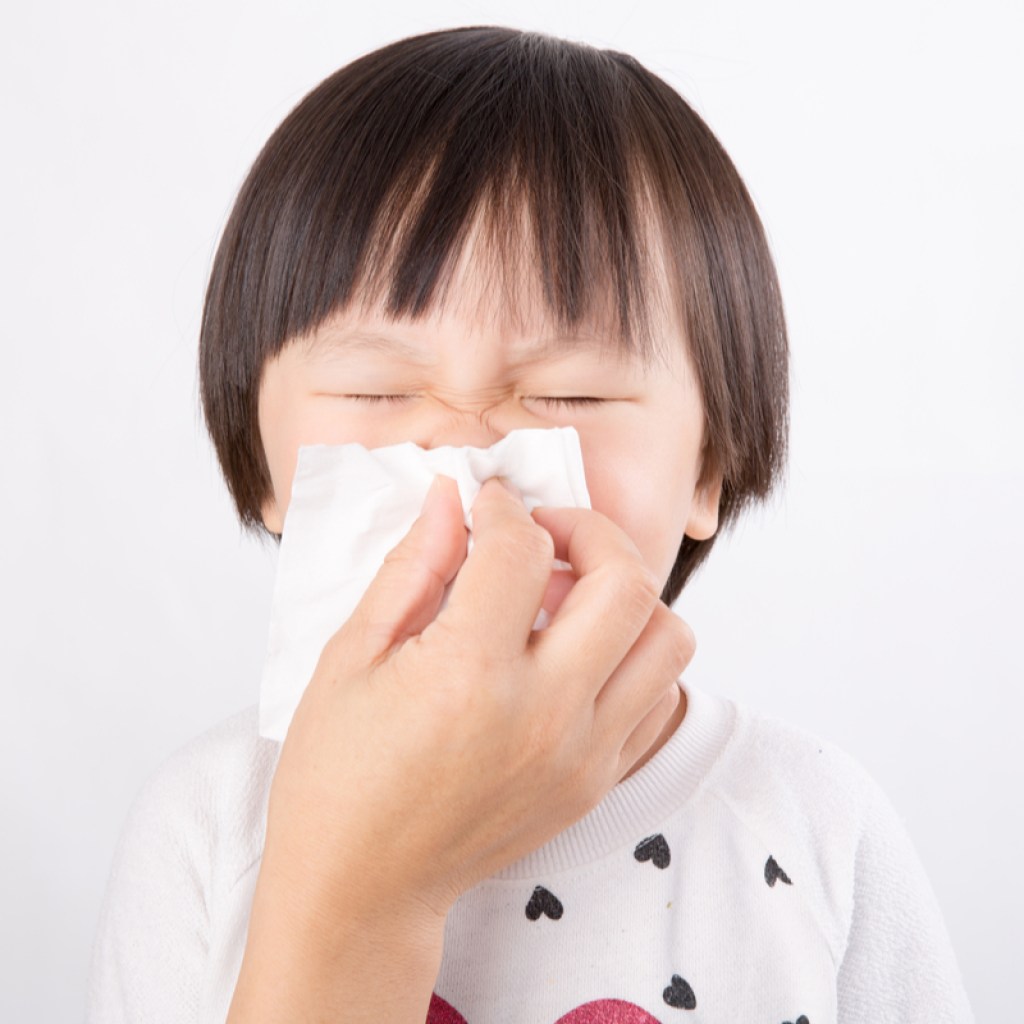 A young child having help blowing his nose.