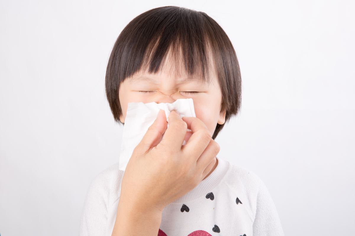 A young child having help blowing his nose.