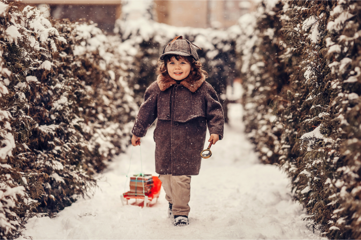 Toddler walking in the snow with a magnifying glass