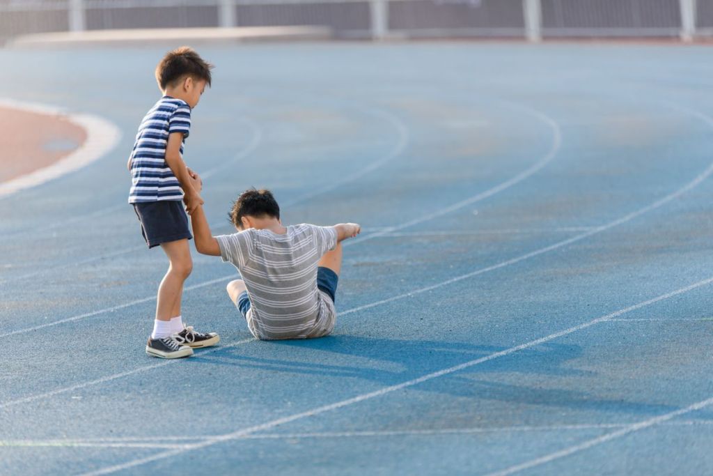 One boy helping another boy to stand up