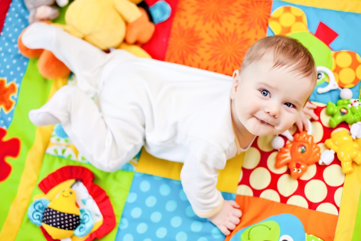 A baby looking up over their shoulder while on a play mat