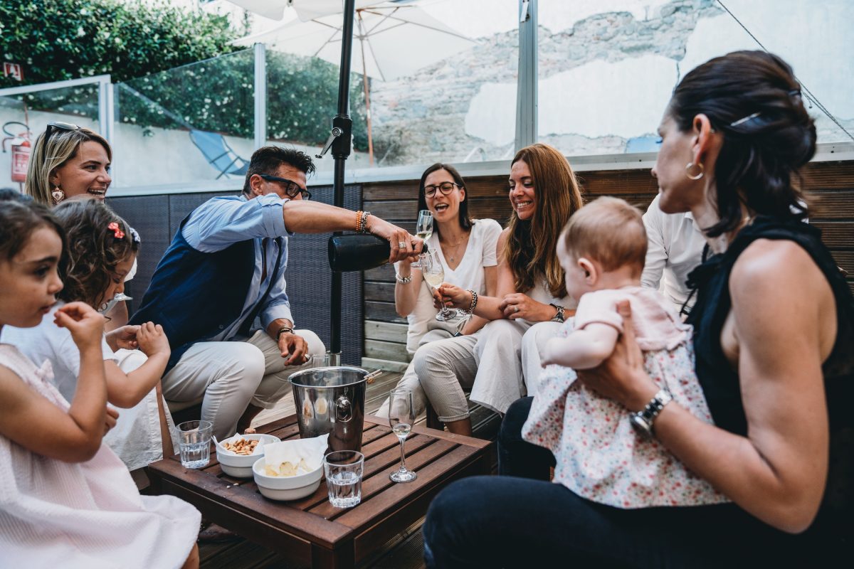 Friends are celebrating together with a bottle of champagne and kids are around