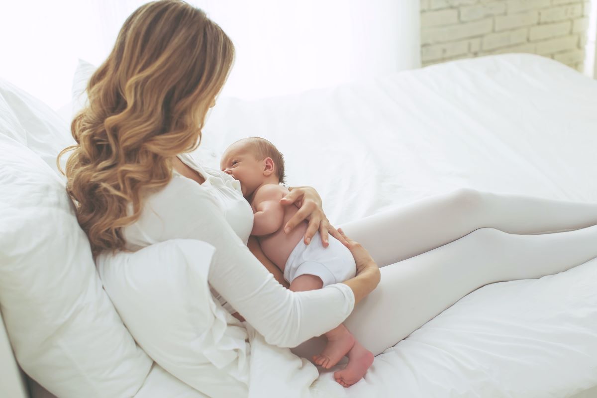 Mom breastfeeding newborn in bed