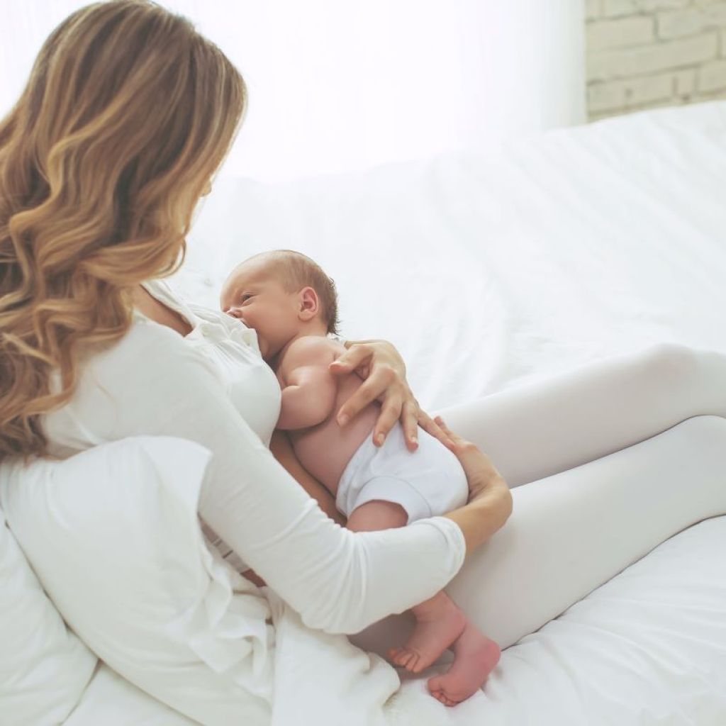 Mom breastfeeding newborn in bed
