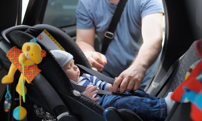 Dad clicking sleeping baby boy into car seat