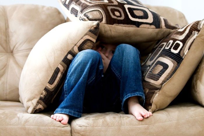 Boy hiding in couch cushions