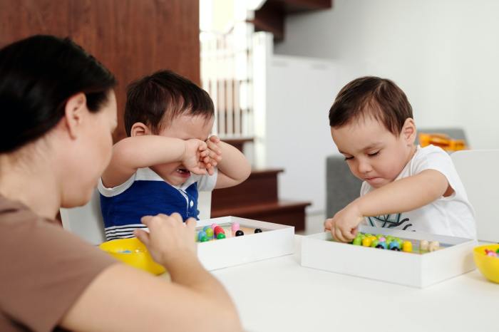 Child crying while playing at table with brothers
