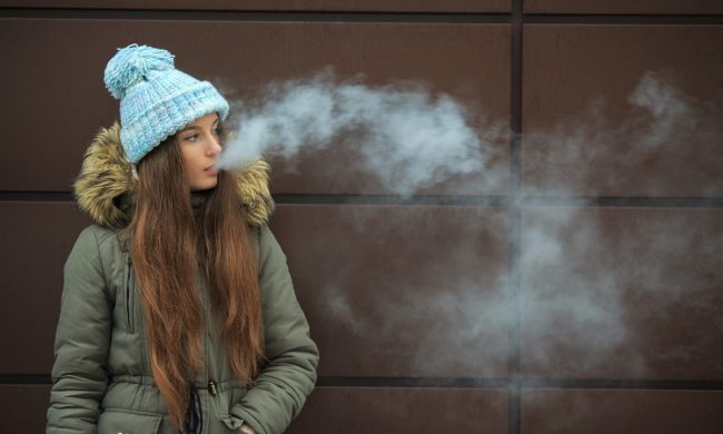 A teen blowing out vape smoke