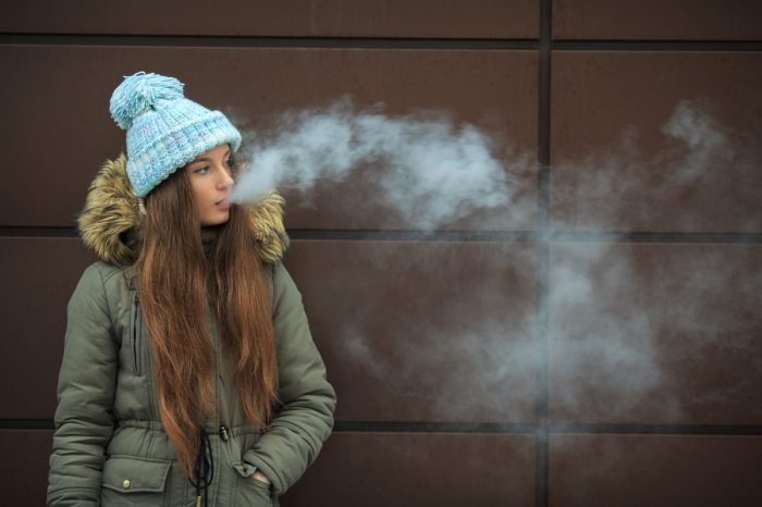 A teen blowing out vape smoke