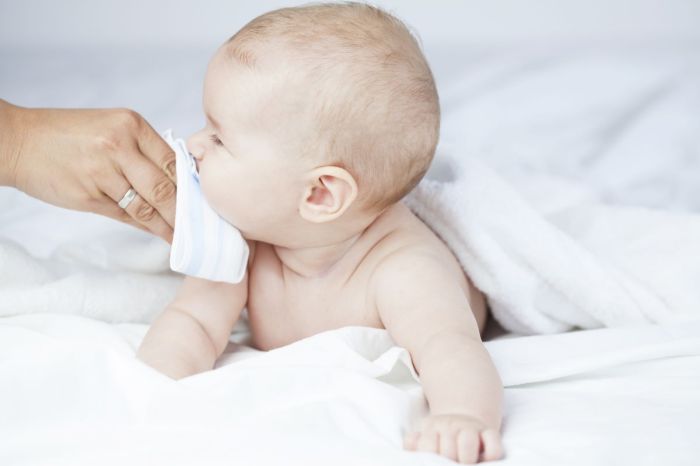 Woman's hand wiping baby's nose