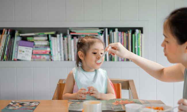 Mom feeding daughter with spoon