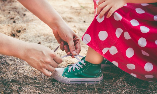 A parent teaching a toddler girls how to tie her sneaker