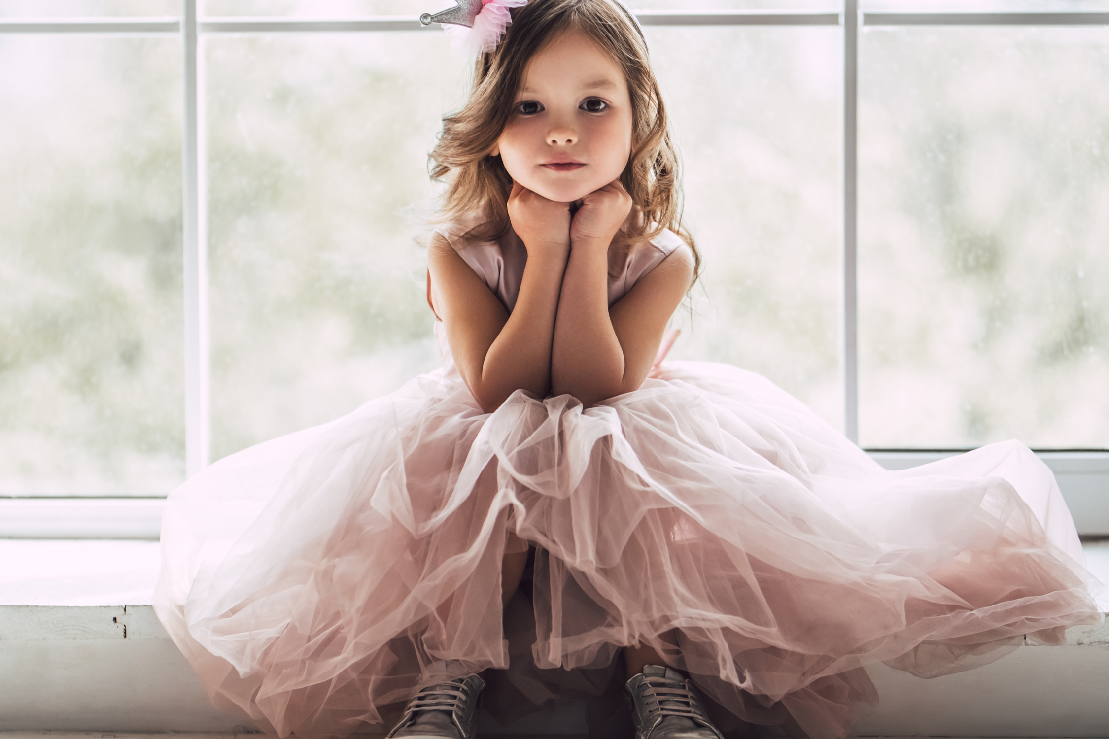 Likttle girl sitting with her hands under her chin