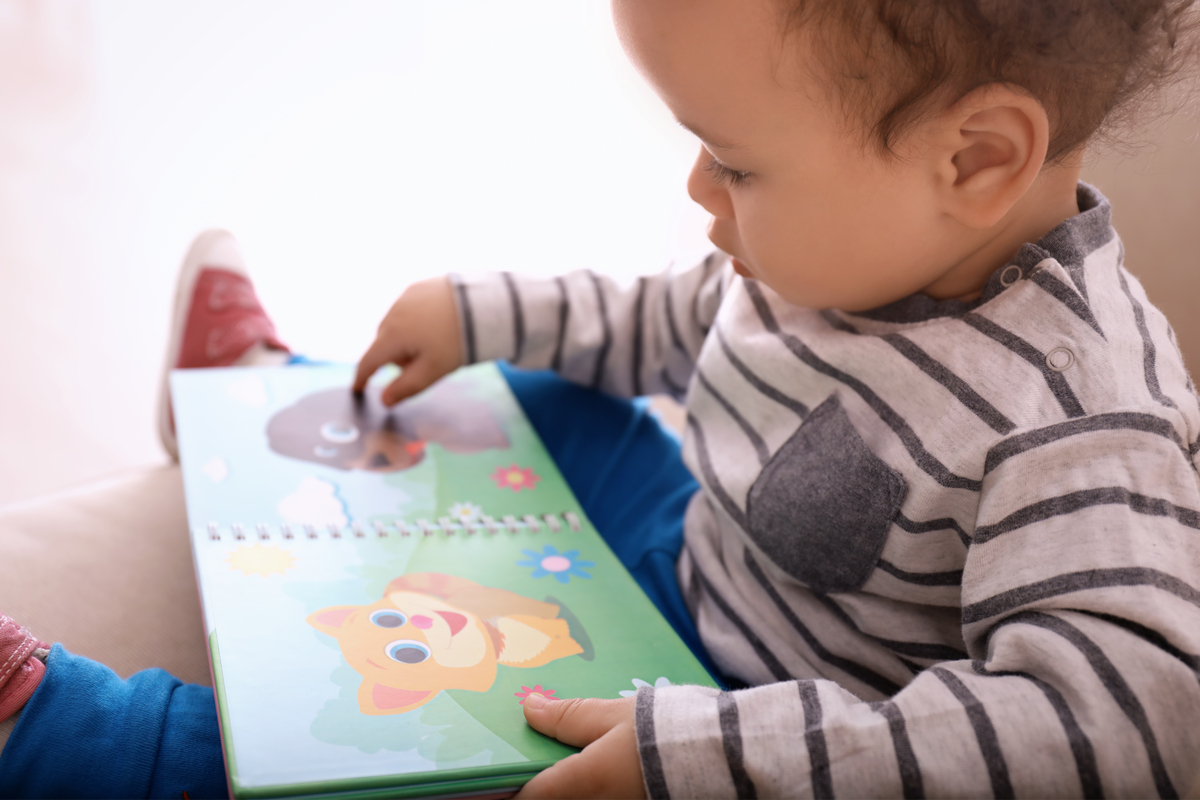 happy toddler boy reading a picture book