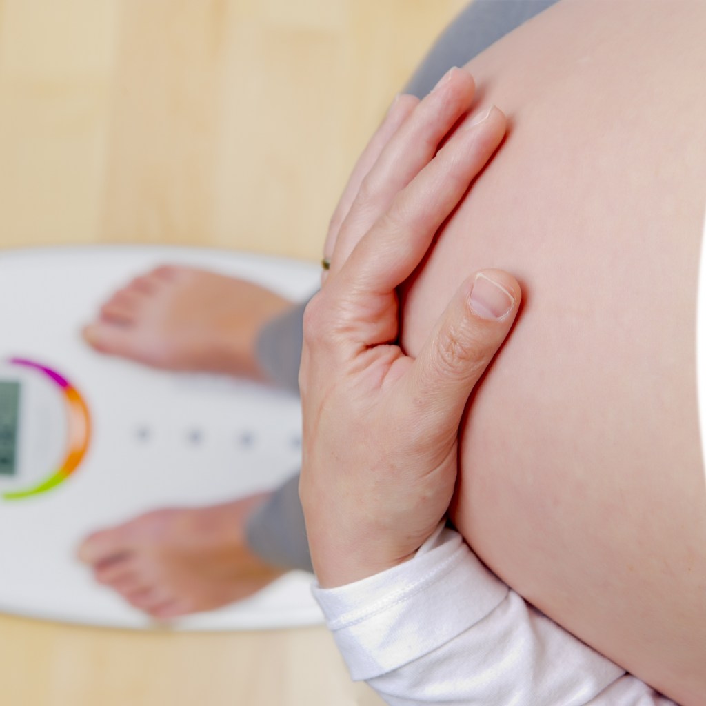 Pregnant woman standing on scale