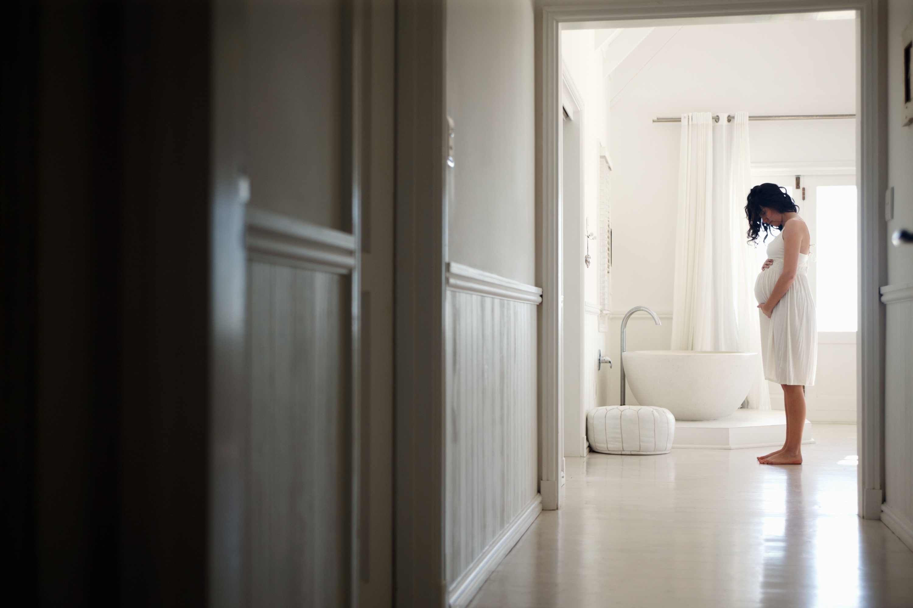 A pregnant woman holding her belly in a bathroom