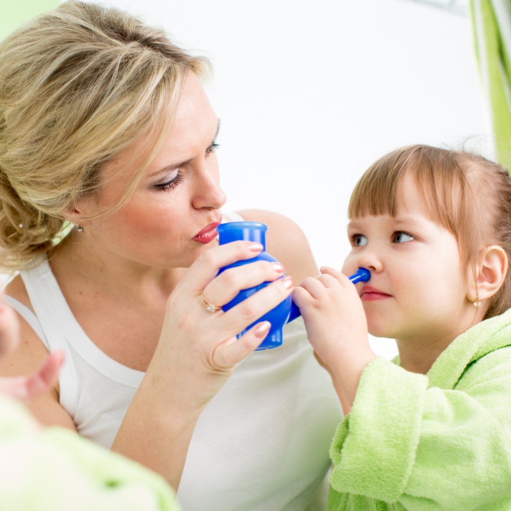 mom helping little girl use a neti pot to help ease allergy symptoms