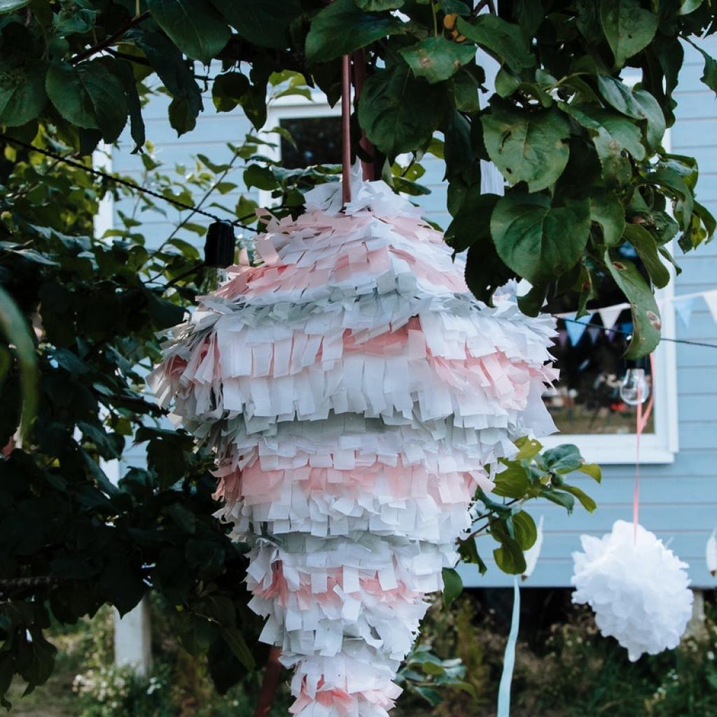 A pink and blue pinata hanging from a tree