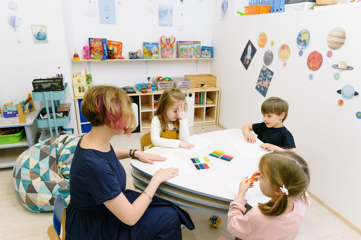 Teacher sitting at a table with preschool students