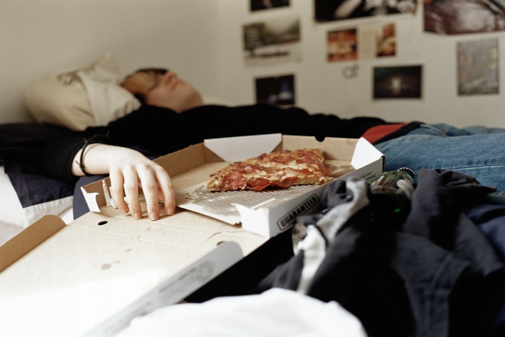 Teen sleeping with pizza on bed
