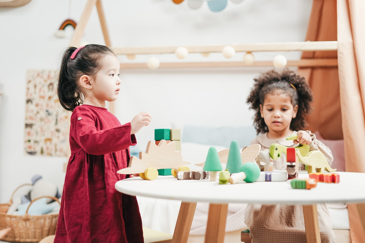 Two toddlers playing with toys on a table.