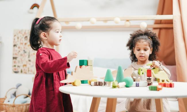 Two toddlers playing with toys on a table
