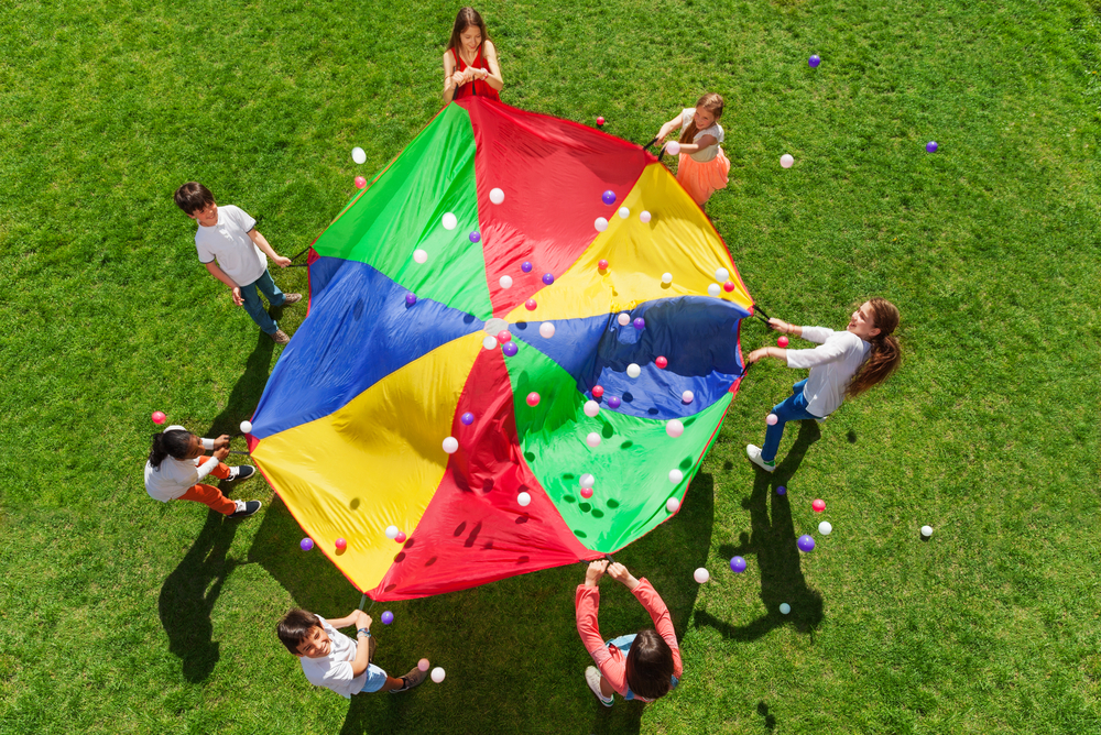 Kids standing in a circle playing a parachute game
