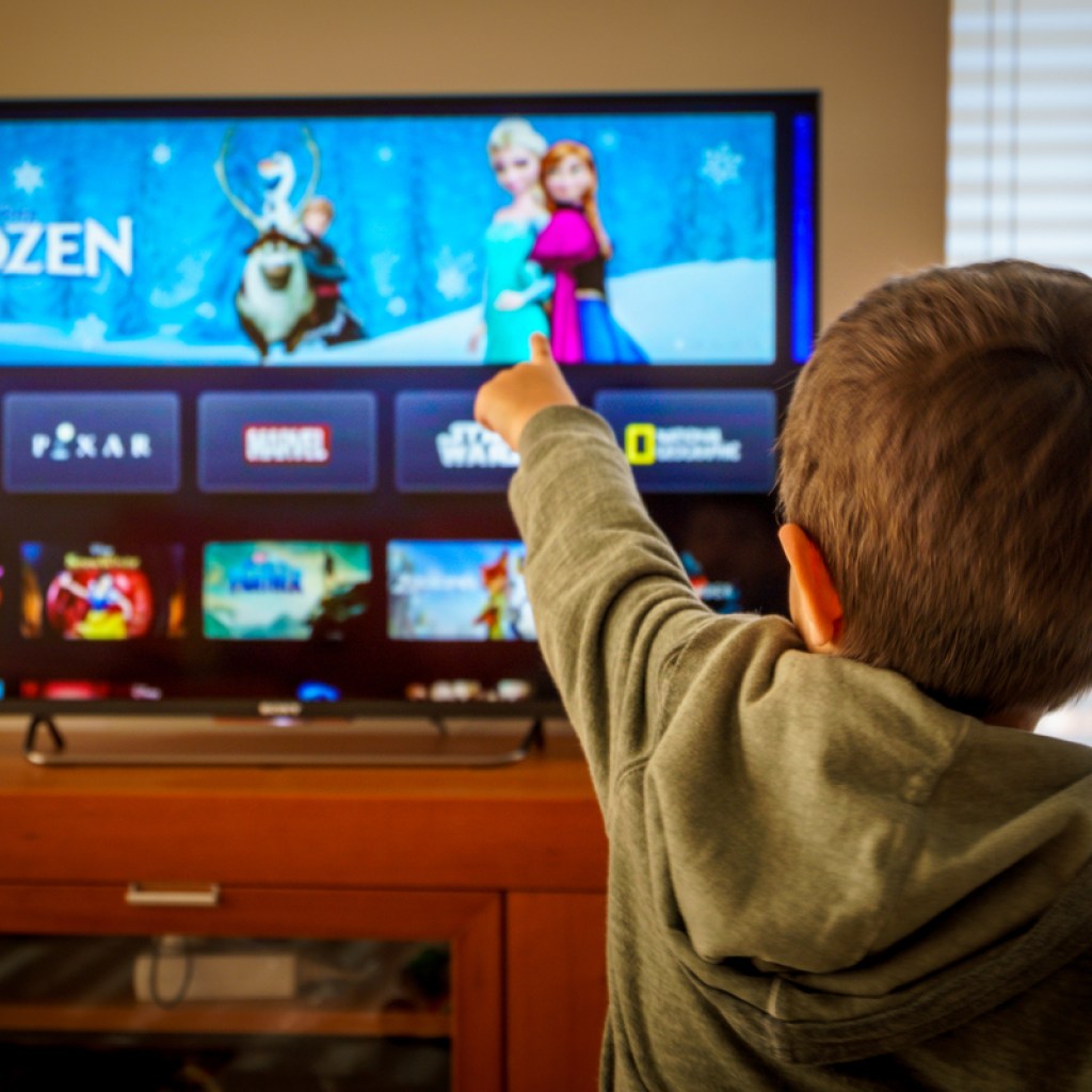 A boy pointing to which Disney movie he wants to watch on TV