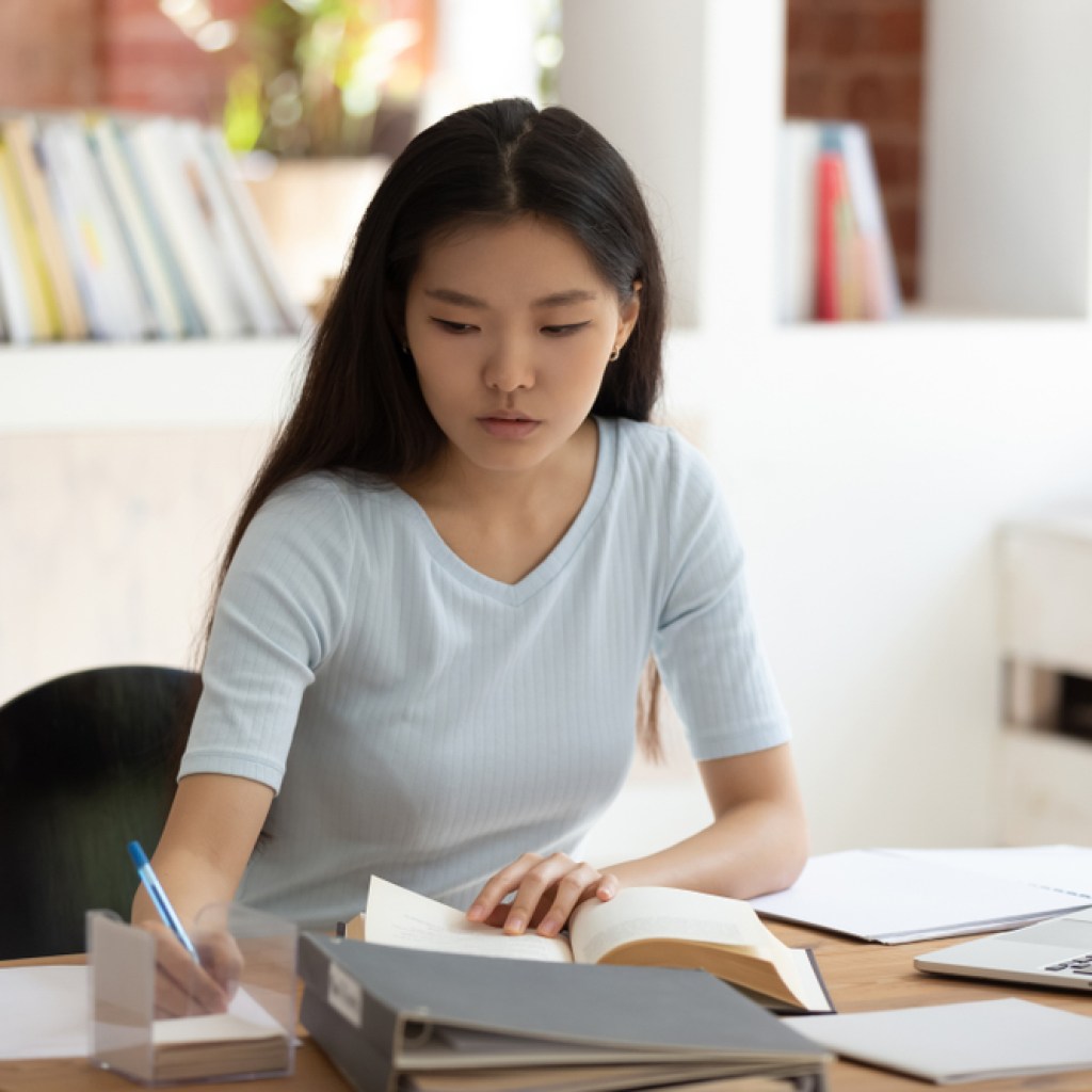 Teenager taking notes from a book to study
