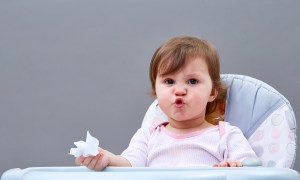 A little child holding a tissue in their hand and crinkling their face up.