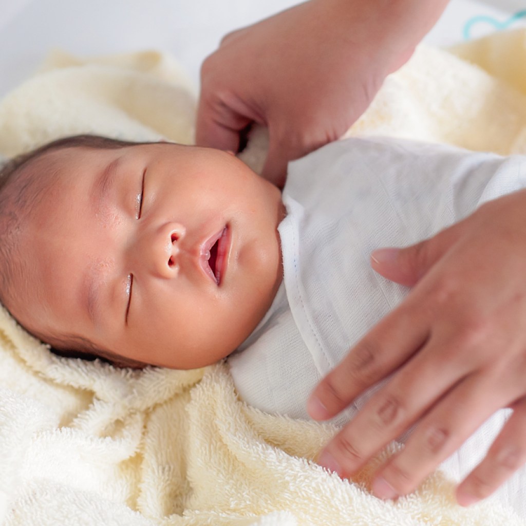A sleeping baby being swaddled