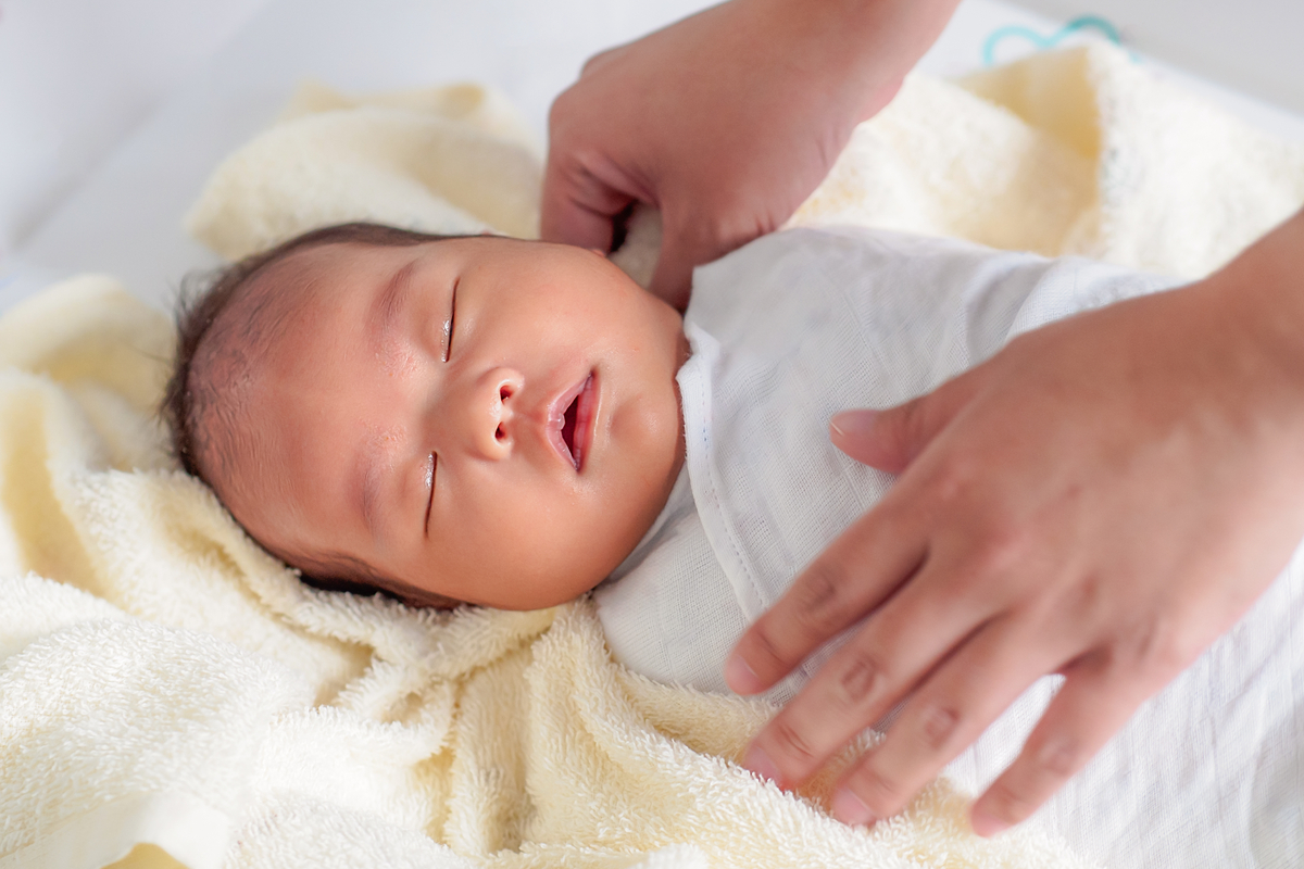 A sleeping baby being swaddled