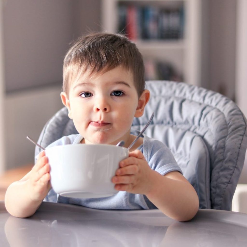 A young toddler holding up a bow for more food.