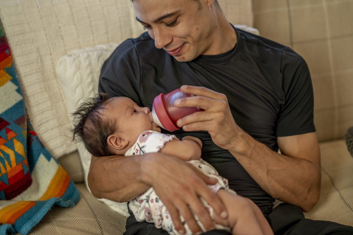 A parent bottle feeding a little baby.