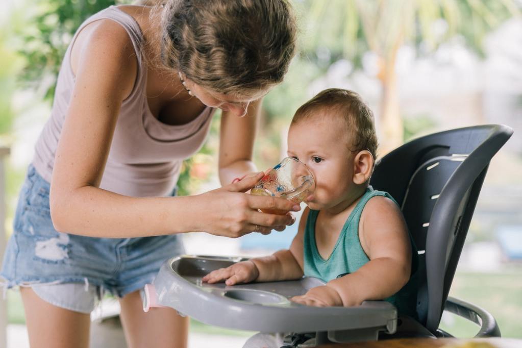 Mom holding a cup while baby drinks from it