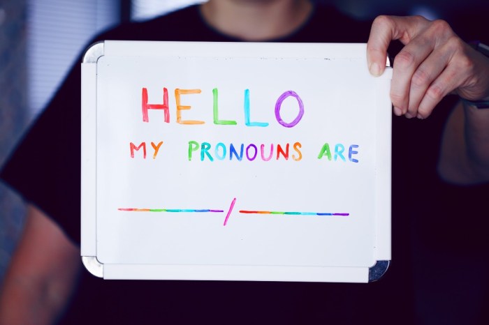 A child holding up a whiteboard that says, "Hello, my pronouns are"