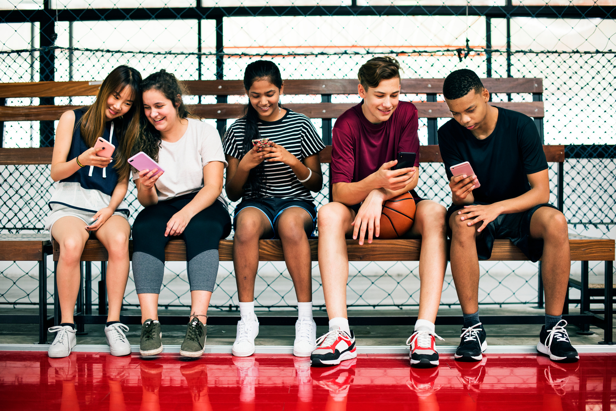 A group of teens looking at their phones.