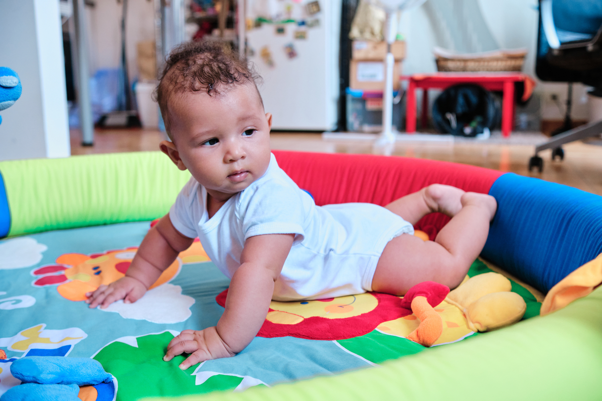A little baby on their stomach on a play mat