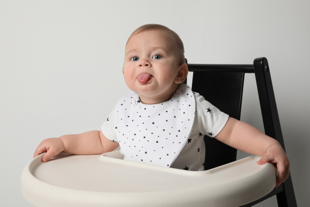 A baby sticking out their tongue and wearing a bib.