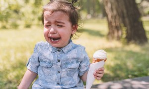 A crying toddler holding an ice cream cone