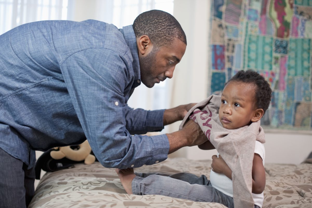 A parent putting clothes on a little baby.
