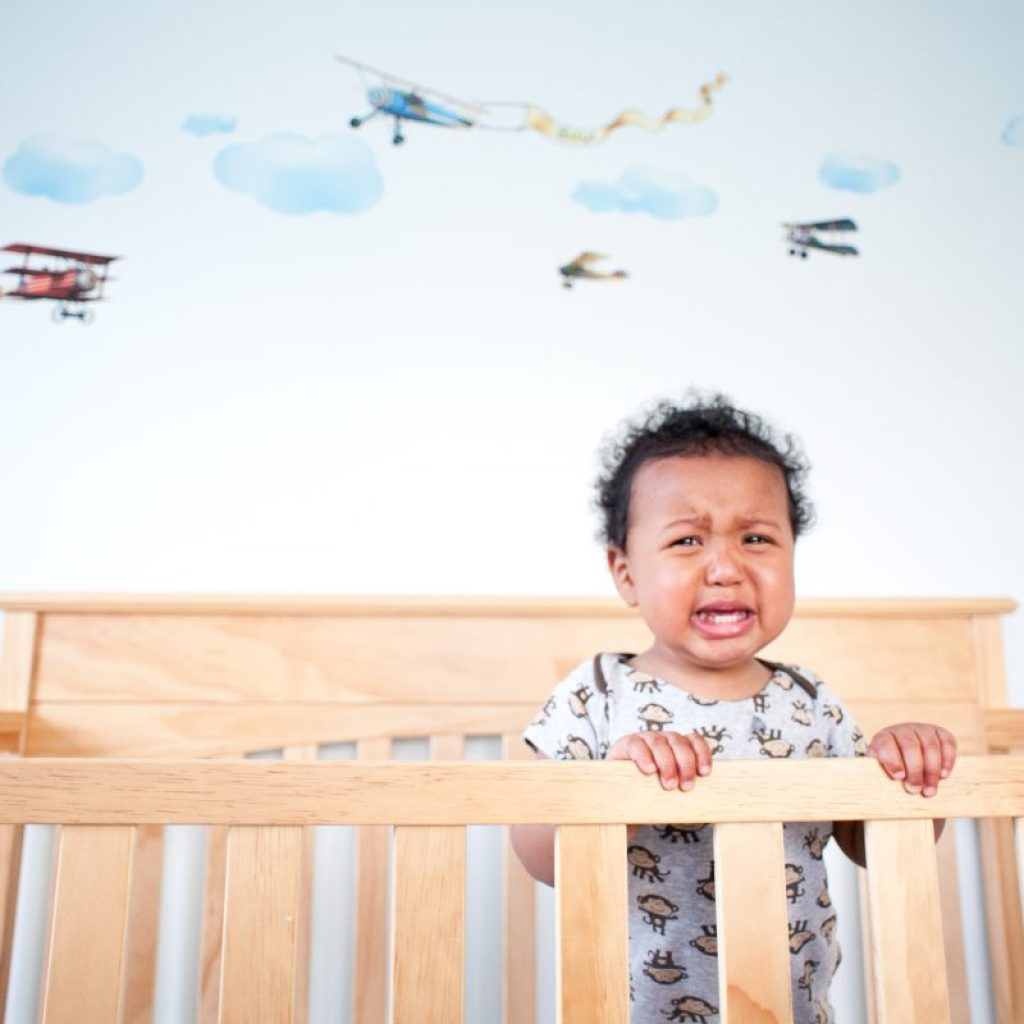 A toddler waking up crying in their crib