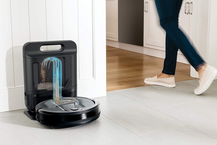 Person walking past Shark IQ self-emptying robot vacuum at docking station