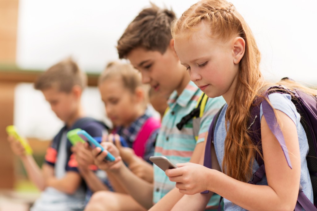 Group of tweens all using cellphones.