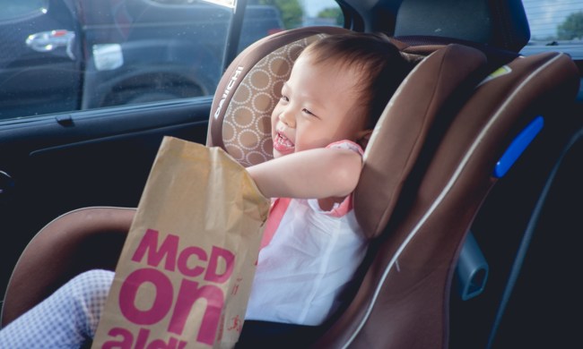 A toddler reaching into a bag of fast food in the car