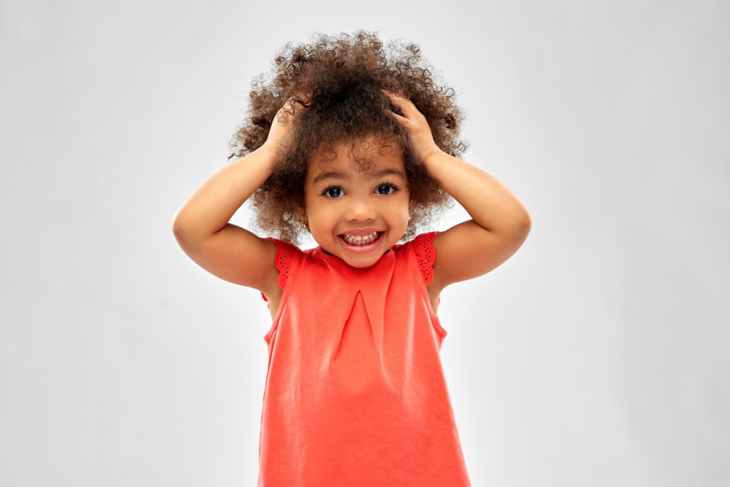 A little girl with her hands in her hair.